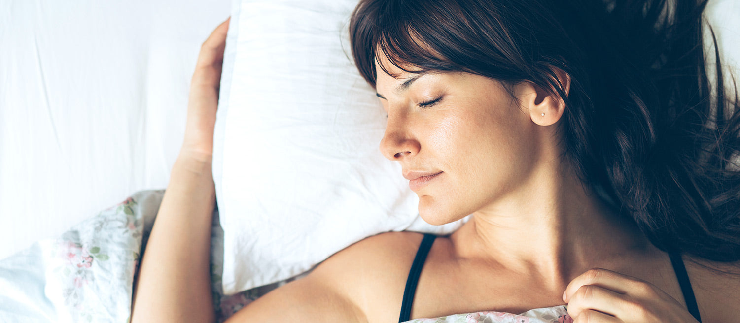 Dark haired women choosing to sleep in panties lying on her side with one arm around her pillow and the other lying on her chest